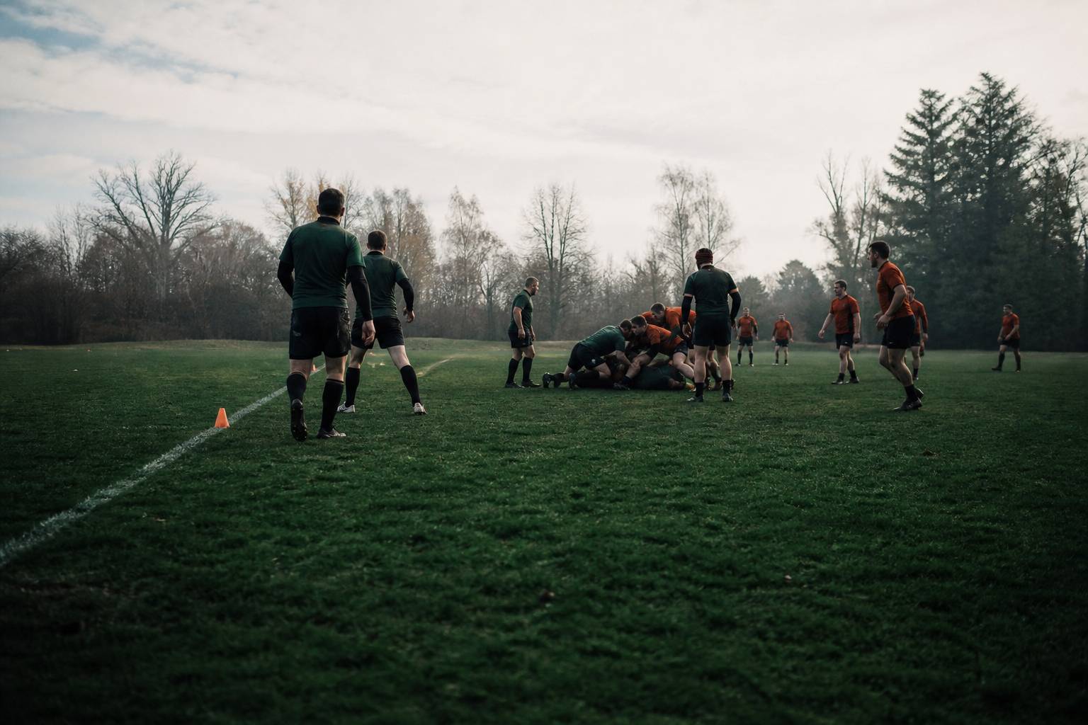 Joueurs de rugby en ruck vus de loin près d'une ligne de craie