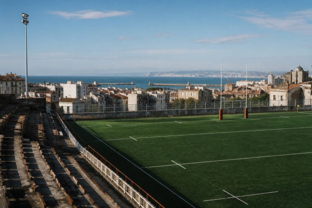 Stade de rugby urbain avec tribunes proches et pelouse verte